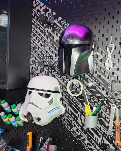 Cascos de Mandalorian y Stormtrooper impresos en 3D colgados en la pared del taller
