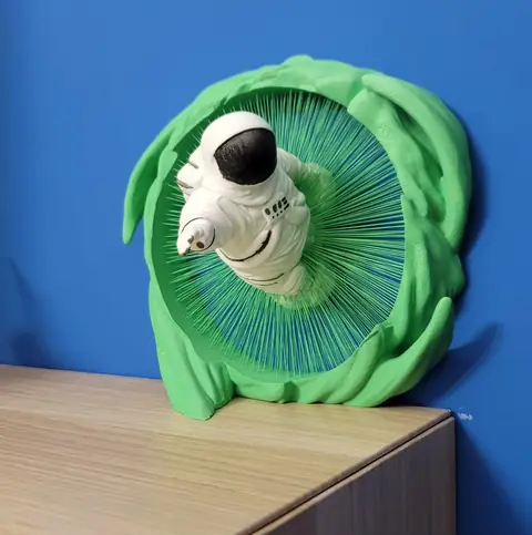 Pieza de pared de un astronauta saliendo de un portal verde, impresa en 3D