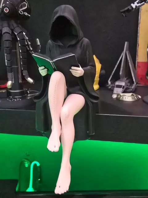 Figura pintada de una mujer encapuchada leyendo en un banco