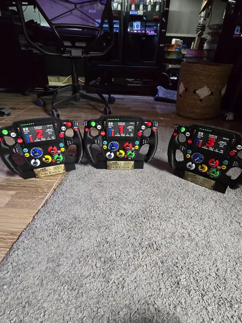 Los tres trofeos volante de F1 alineados sobre una mesa